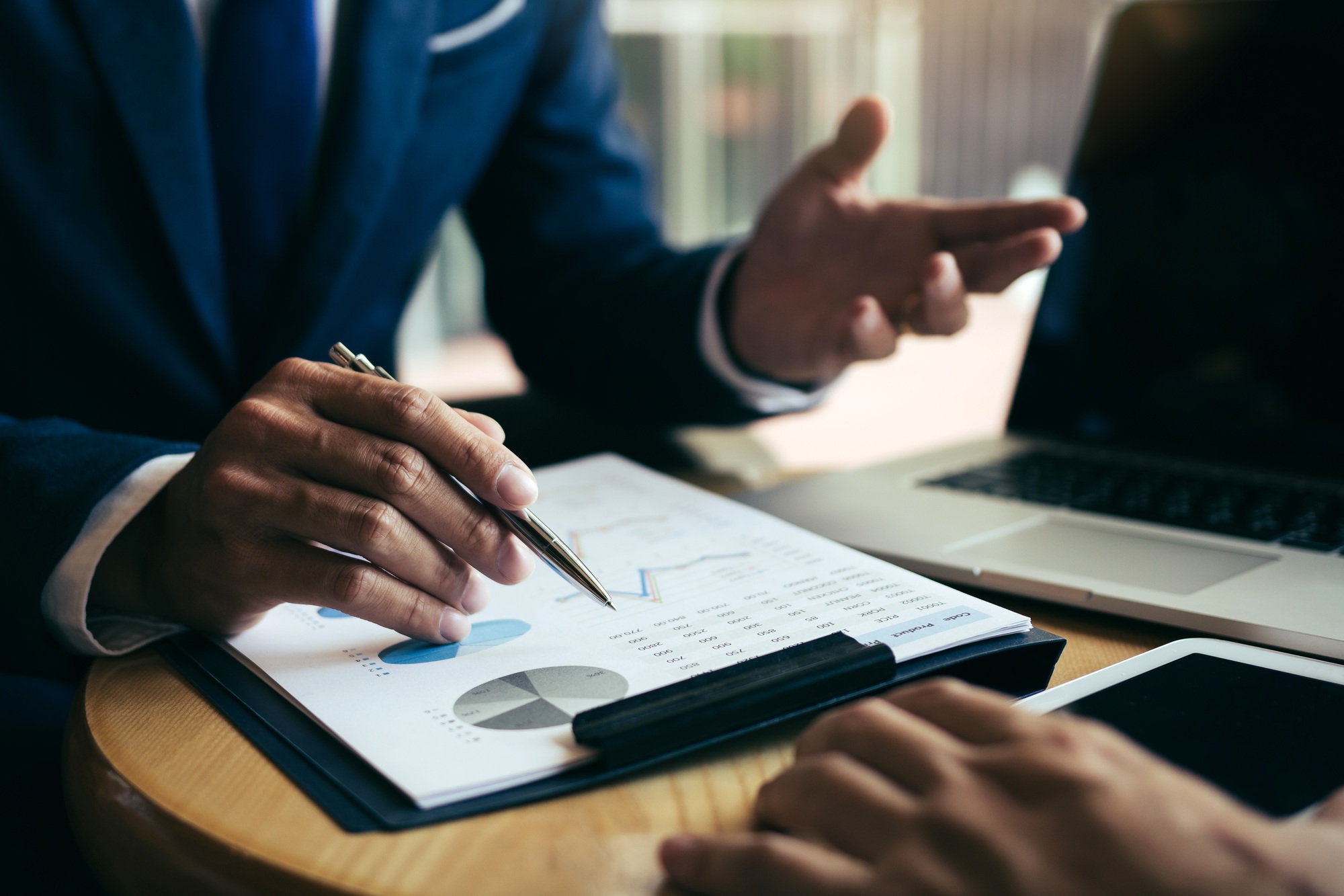 Two businessmen are discussing and analyzing the performance of the company business paper
